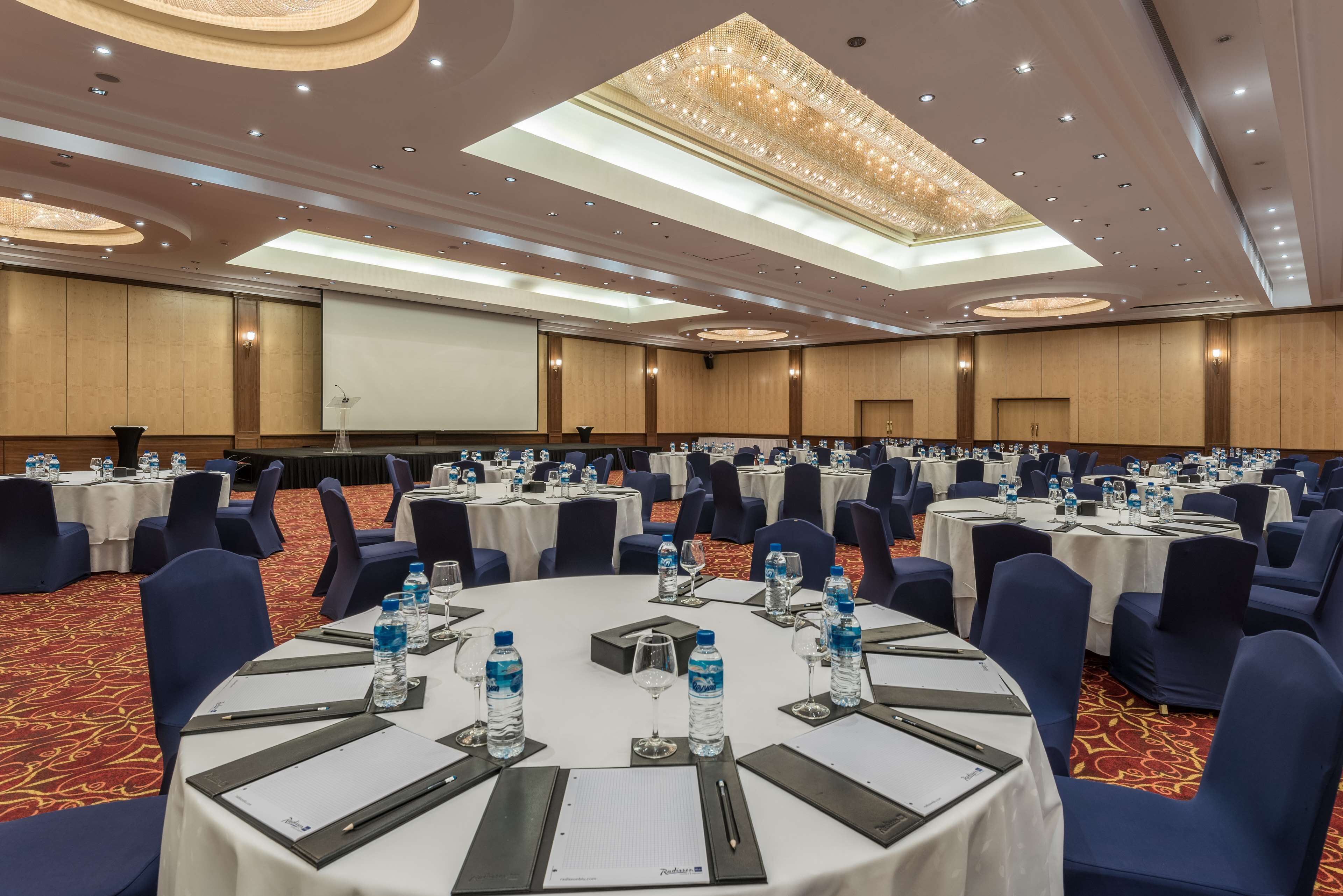 A conference room with round tables, blue chairs, and water bottles.