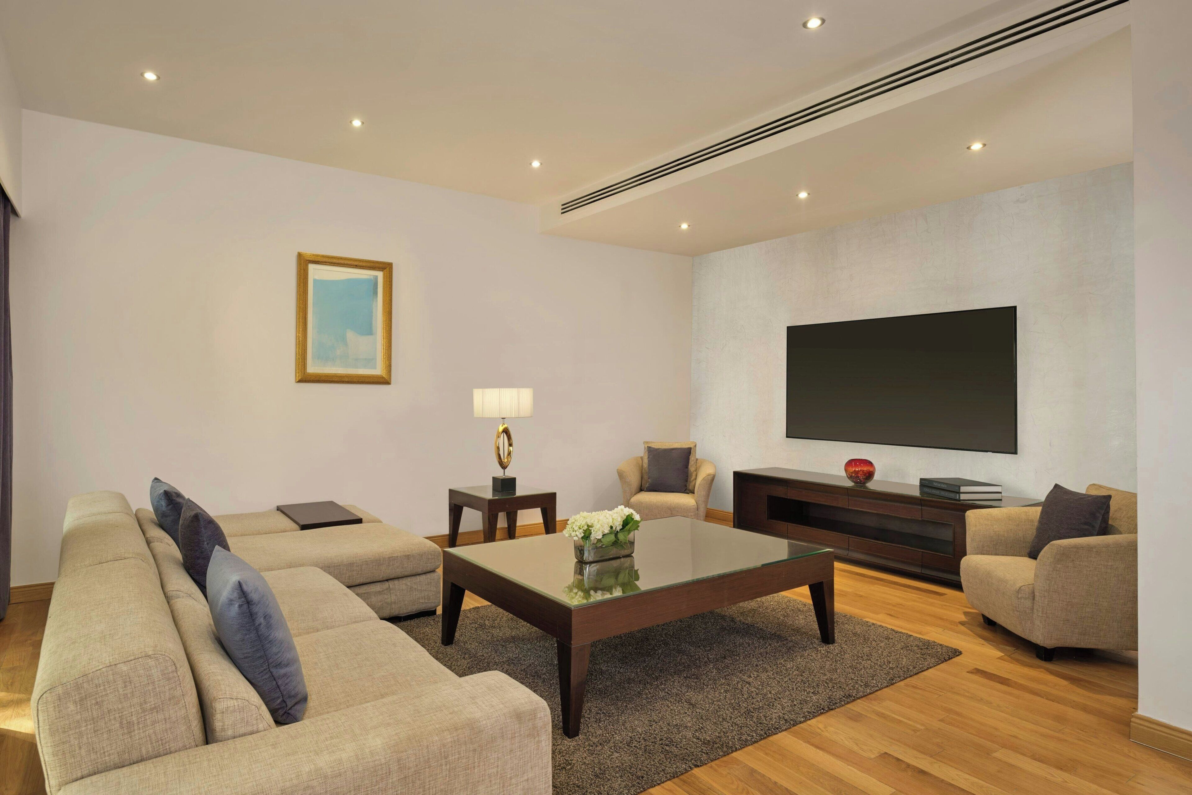 Una sala de estar moderna con un conjunto de sofás, una mesa de centro, un televisor y un cuadro en la pared.