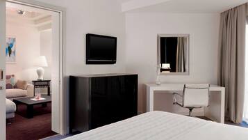Una camera d'albergo con un letto, una scrivania con una sedia, una televisione e uno specchio.