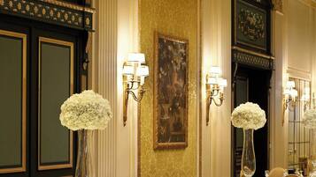 A banquet hall with round tables, gold chairs, and floral centerpieces.