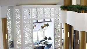 Un vestíbulo moderno con una zona de estar curvilínea, una mesa de centro de vidrio y un separador decorativo blanco.