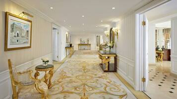 Un hall imponente con muebles dorados ornamentados, una alfombra estampada y un cuadro grande en la pared.