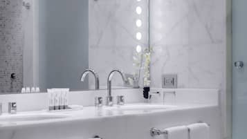 Une salle de bain moderne avec un grand miroir, deux lavabos et un espace douche.