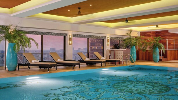 Un área de piscina interior moderna con sillones de descanso y grandes macetas.
