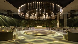 A spacious, modern lobby with a circular seating area, a large chandelier, and a stage with a backdrop. - Le Meridien Dubai Hotel & Conference Centre (Dubai)