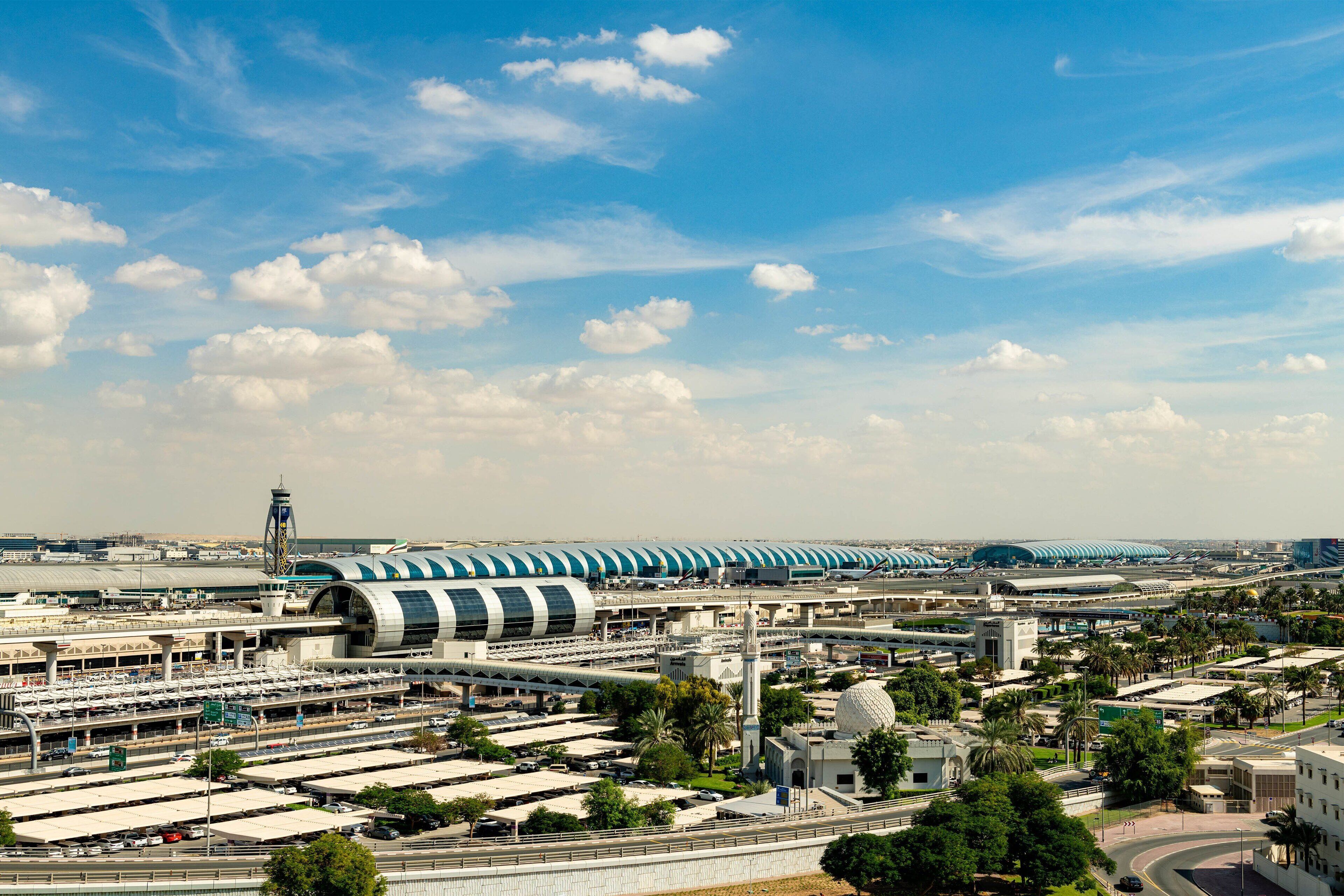 Um terminal de aeroporto moderno com vários níveis, passarelas interligadas e um edifício esférico em destaque.