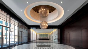 A spacious lobby with a circular marble floor, a large chandelier, and a view of the outside through large windows. - Le Meridien Dubai Hotel & Conference Centre (Dubai)
