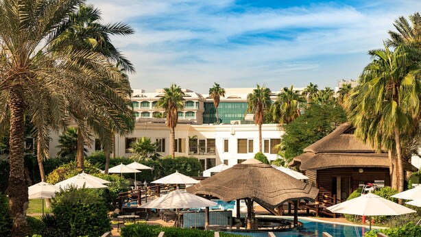 A resort pool area with umbrellas, lounge chairs, and palm trees. - Le Meridien Dubai Hotel & Conference Centre (Dubai)