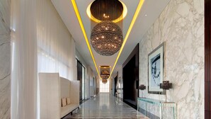 A long, elegant hallway with a marble floor, a plush sofa, and a large, spherical chandelier. - Le Meridien Dubai Hotel & Conference Centre (Dubai)