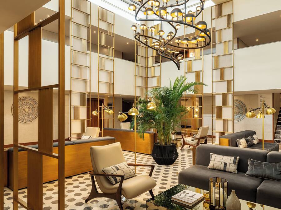 A spacious lobby with a reception desk, seating areas, and a decorative chandelier.