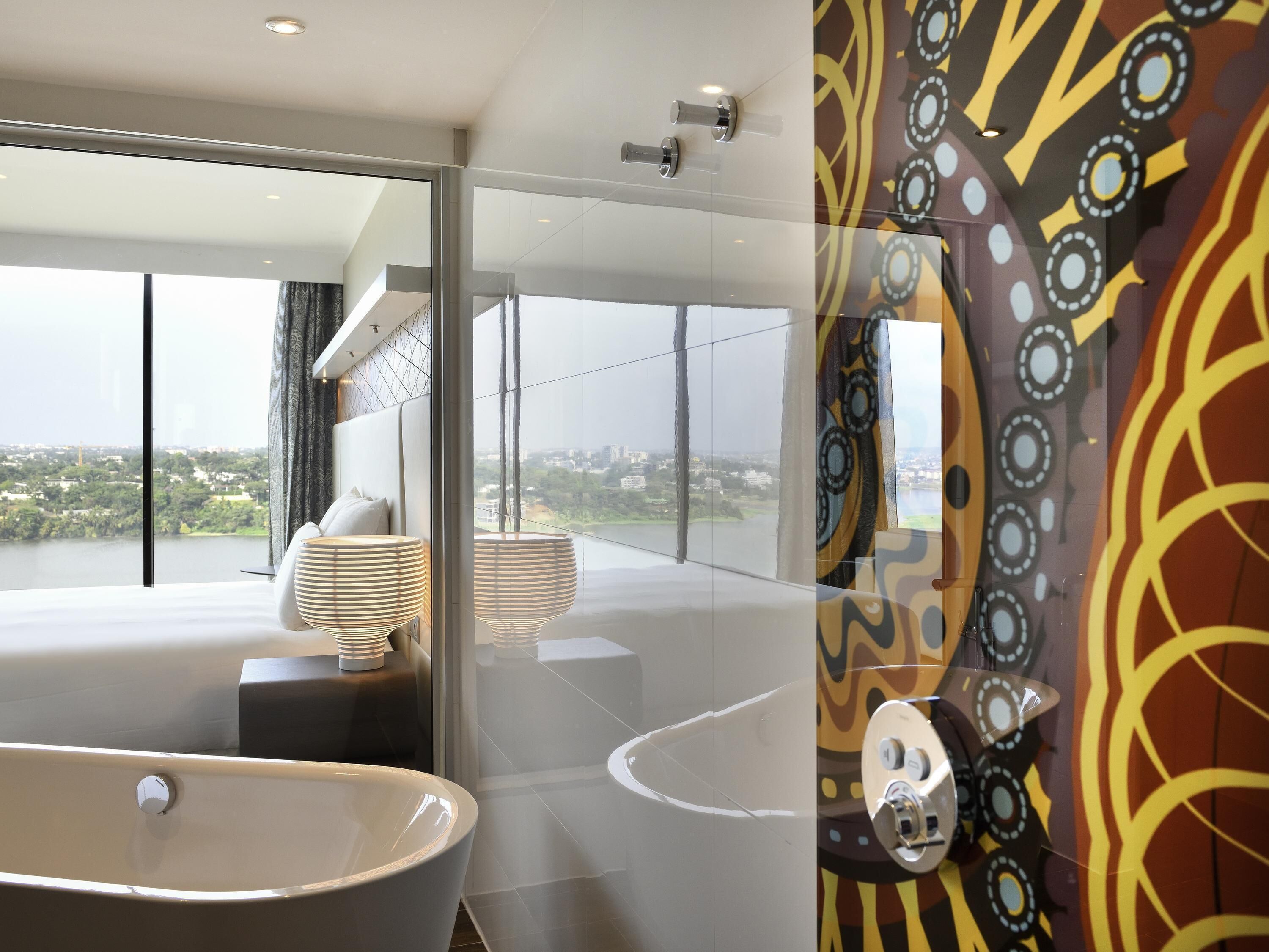 A modern bathroom with a large bathtub, a glass-enclosed shower area, and a view of a cityscape.