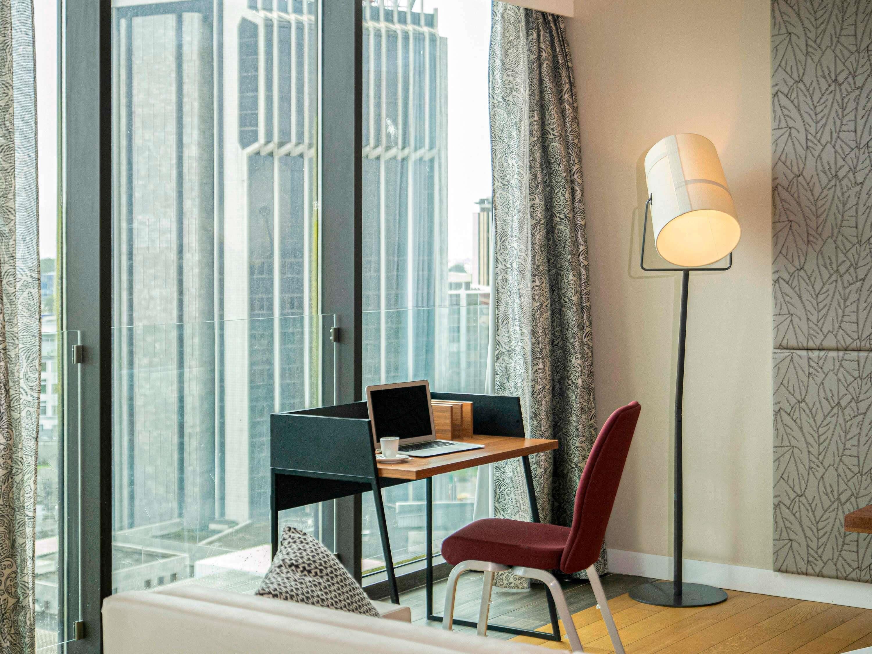 A modern room with a desk, chair, and a floor lamp.