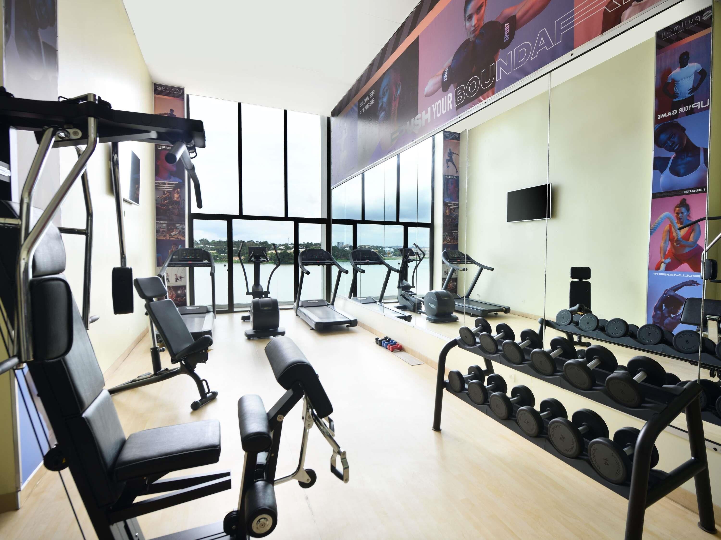 Un gimnasio con equipo de ejercicio, una banca y un estante con mancuernas.