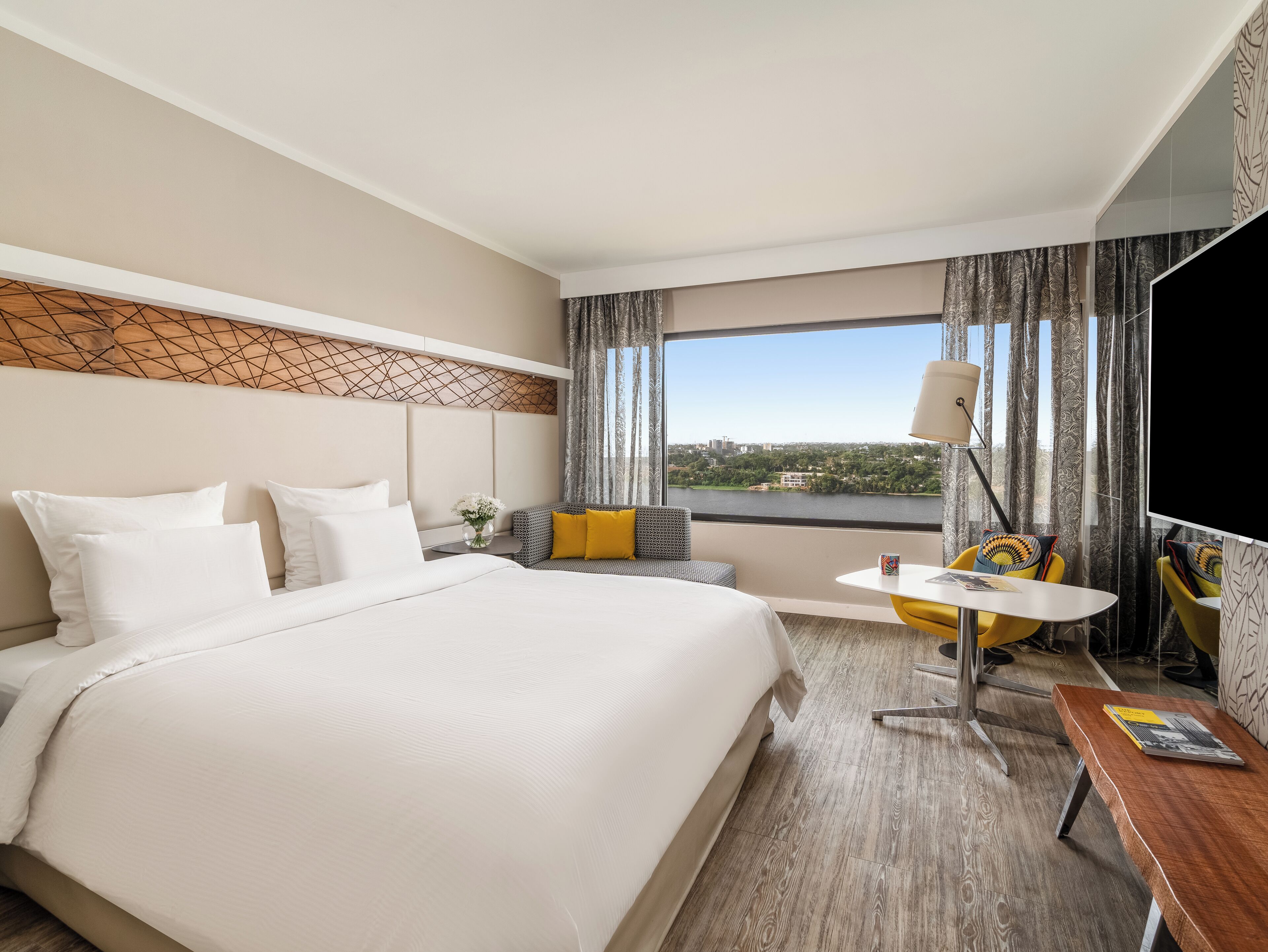 A hotel room with a bed, a seating area, a table, and a TV.