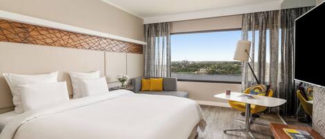 A hotel room with a bed, a seating area, a table, and a TV.