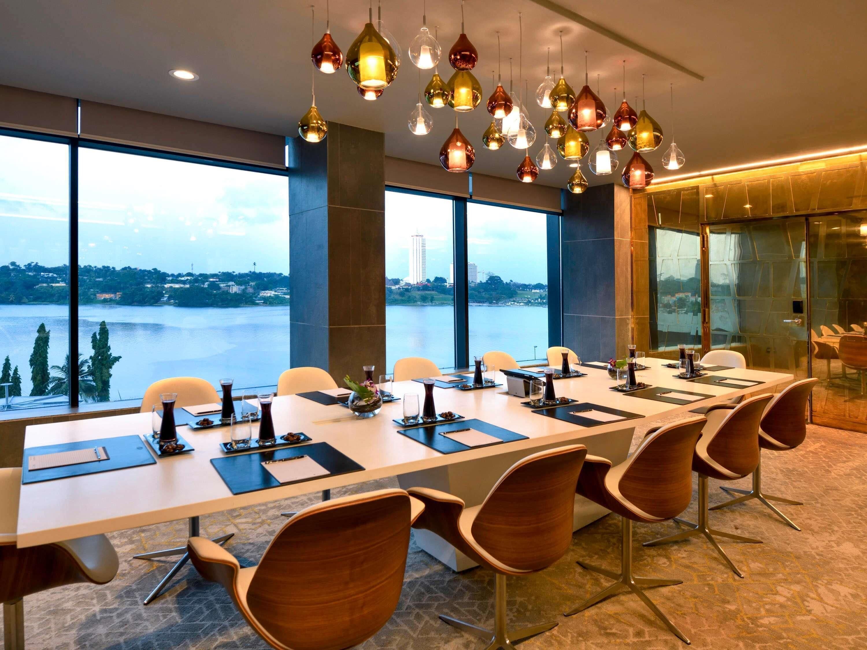 A conference room with a long table, chairs, and a view of a body of water.