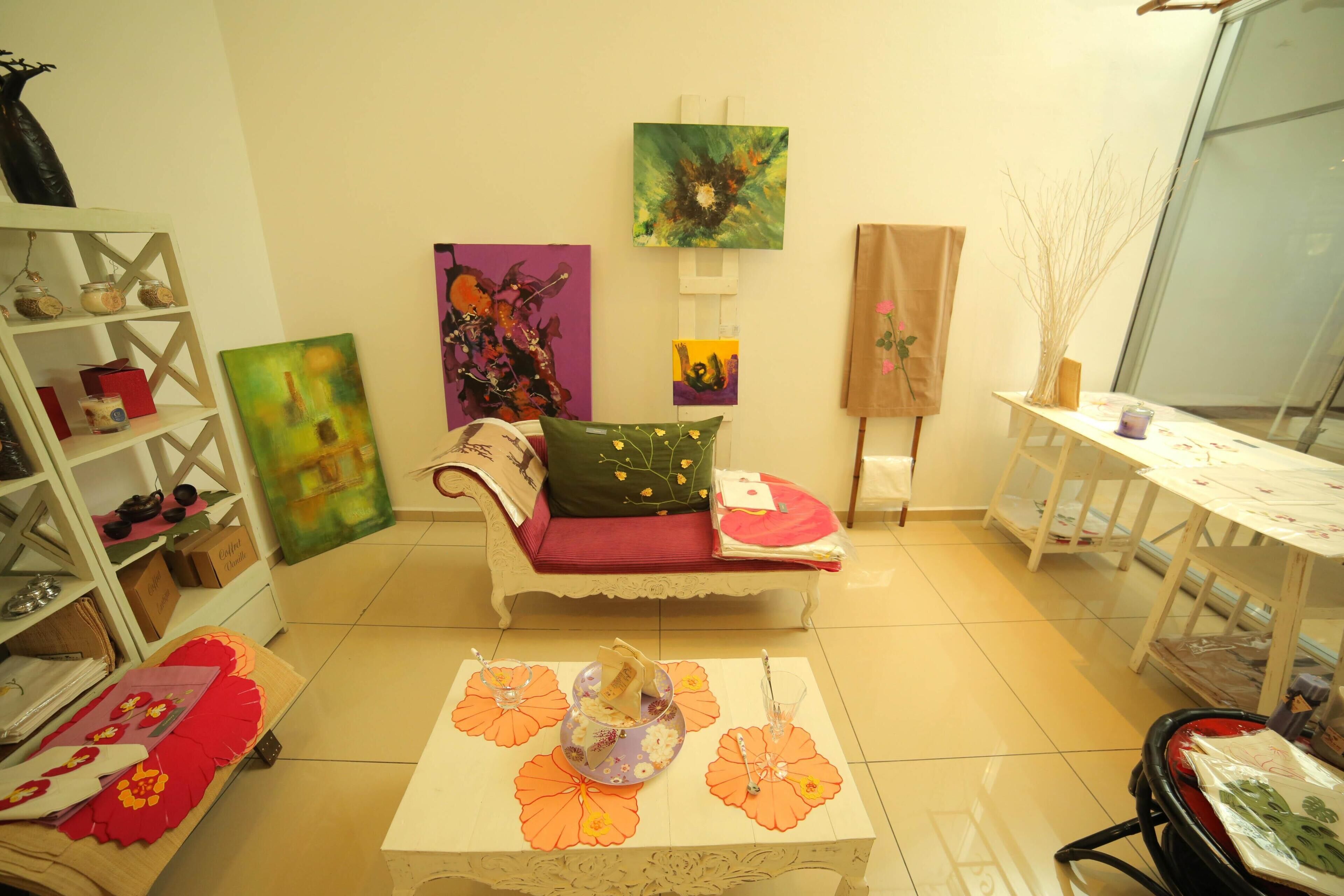 A room with a sofa, a table with placemats, a bookshelf, and artwork on the walls.