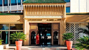 A traditional Moroccan building entrance with intricate tile work and a wooden lattice canopy. - Les Merinides (Fes)