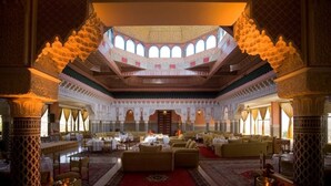 A luxurious interior with a central seating area, high ceilings, and intricate architectural details. - Les Merinides (Fes)