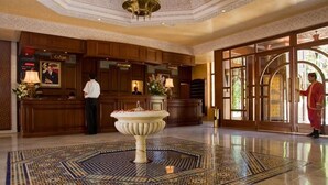 A lobby with a reception desk, a decorative fountain, and a patterned floor. - Les Merinides (Fes)