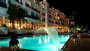 A hotel with a swimming pool, palm trees, and a night-time setting. - Les Merinides (Fes)