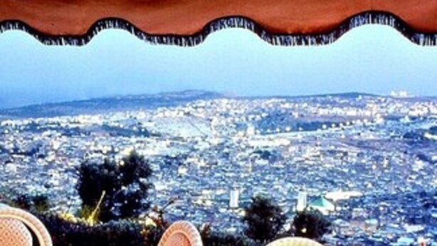 A dining area with tables set for two, overlooking a cityscape. - Les Merinides (Fes)