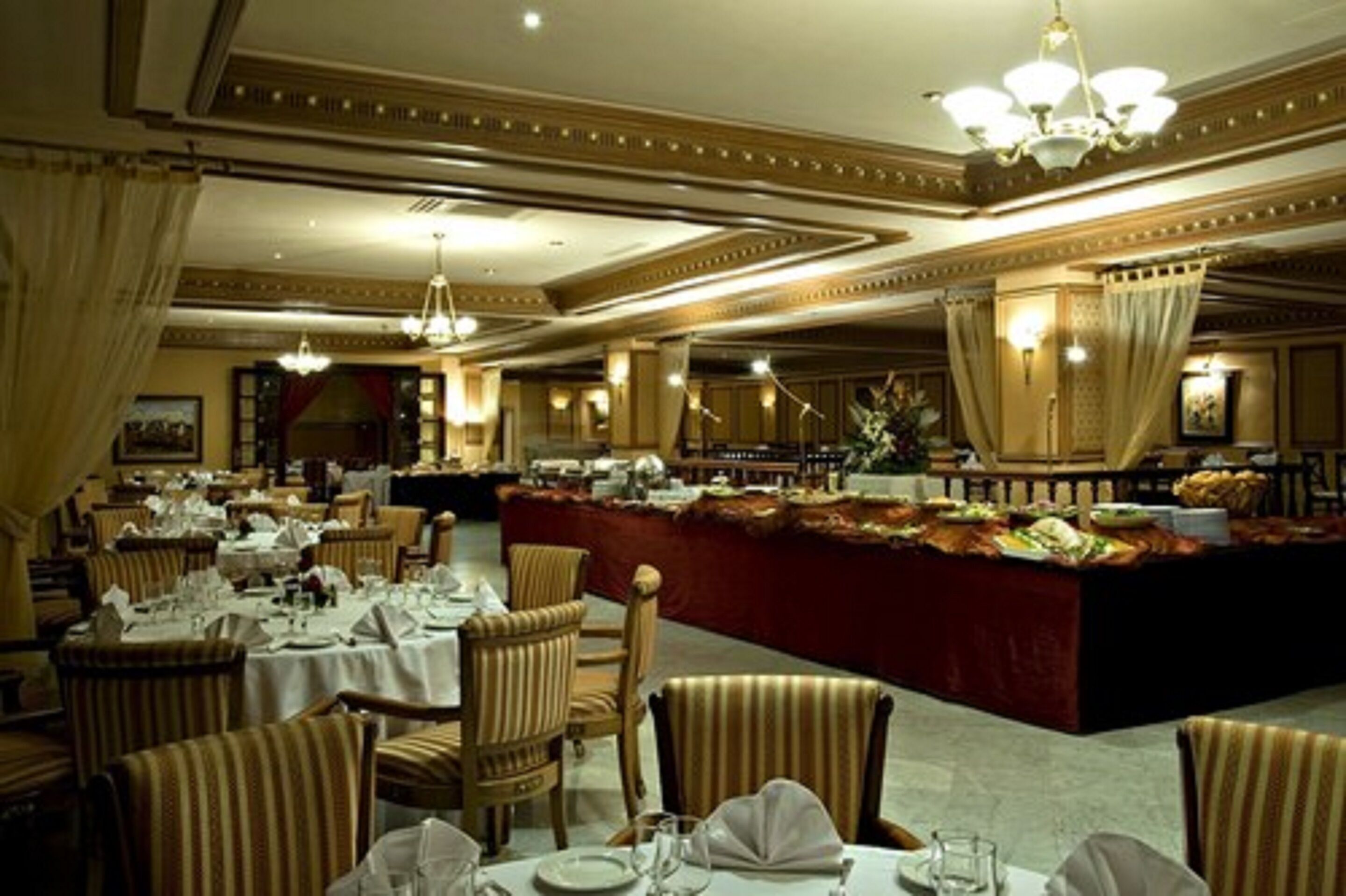 A formal dining area with round tables, chairs, and a central buffet.