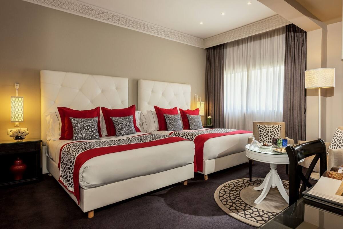 A hotel room with two beds, a round dining table, and a chair.