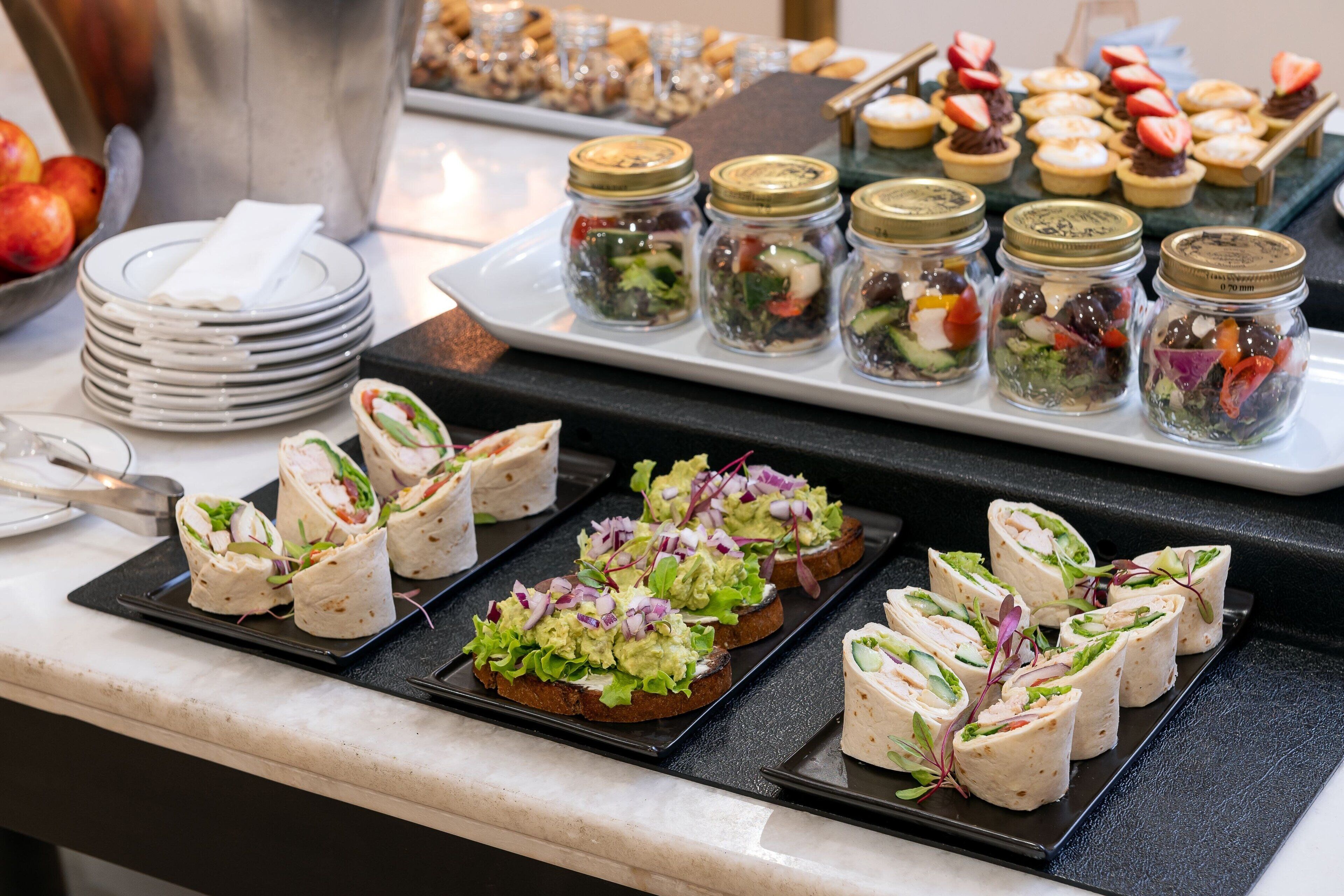 Un buffet proposant une variété de plats, notamment des sandwichs, des salades et des desserts.