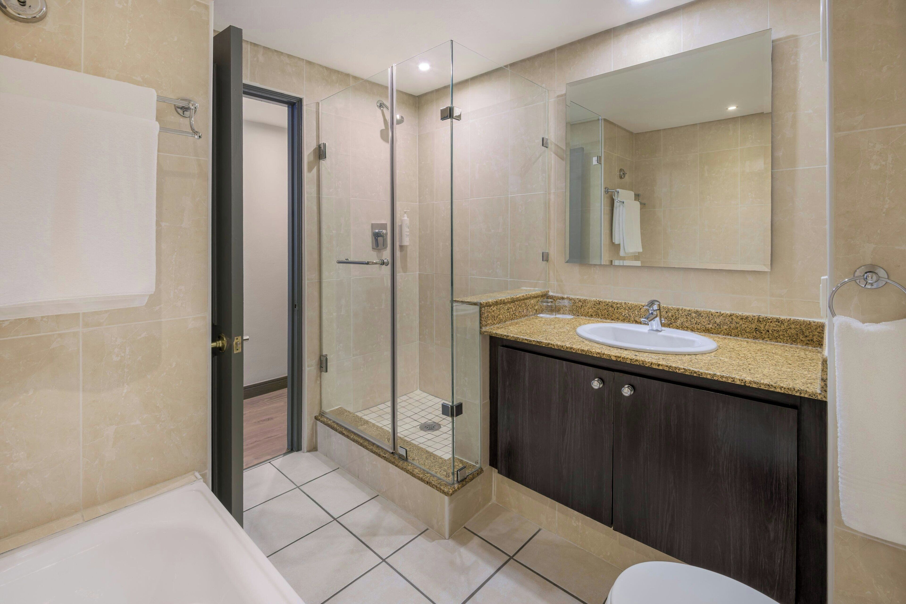 A modern bathroom with a glass-enclosed shower, a sink, and a large mirror.
