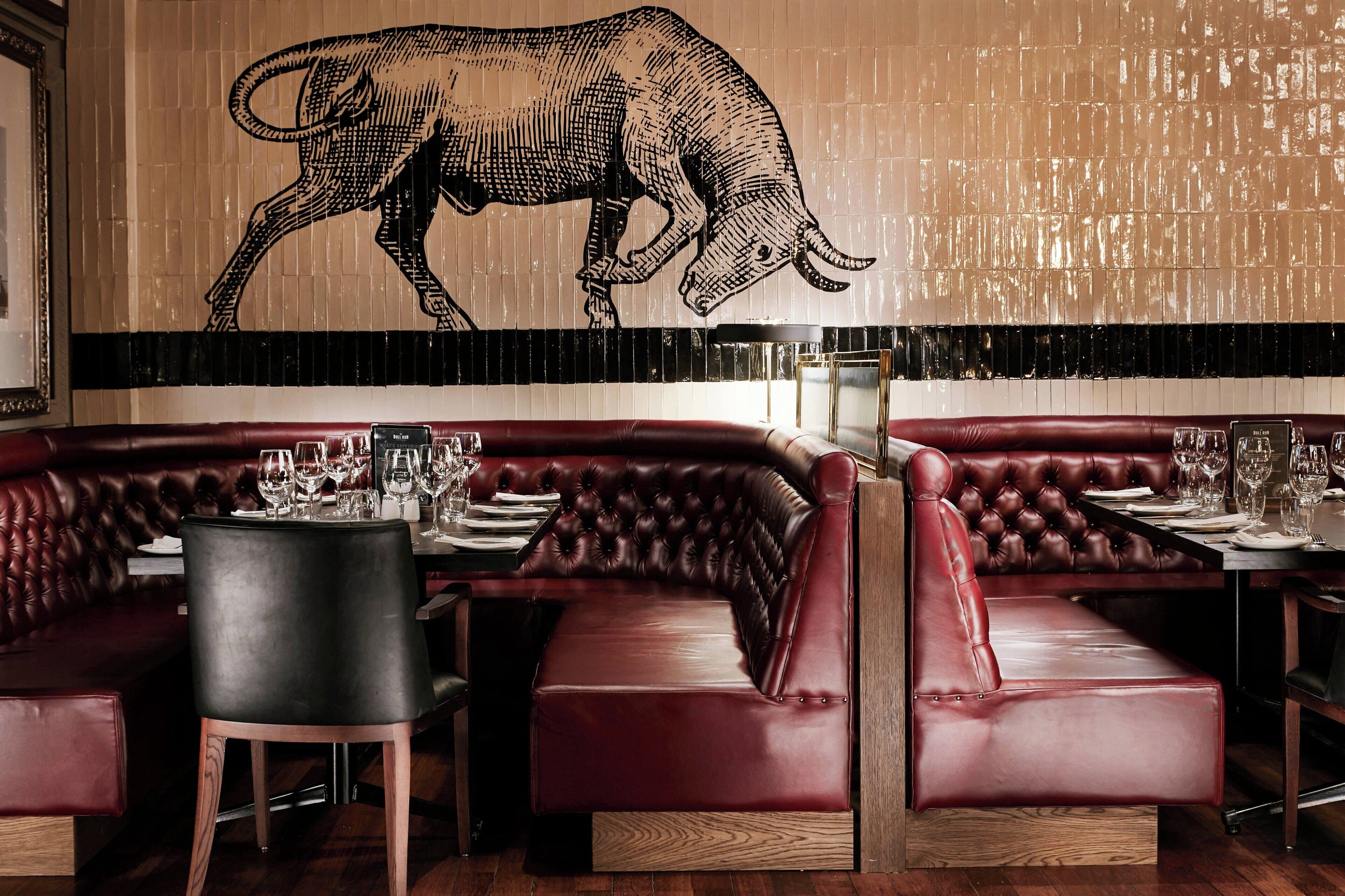 Un restaurante con asientos de cuero y un gran mural de un toro en la pared.