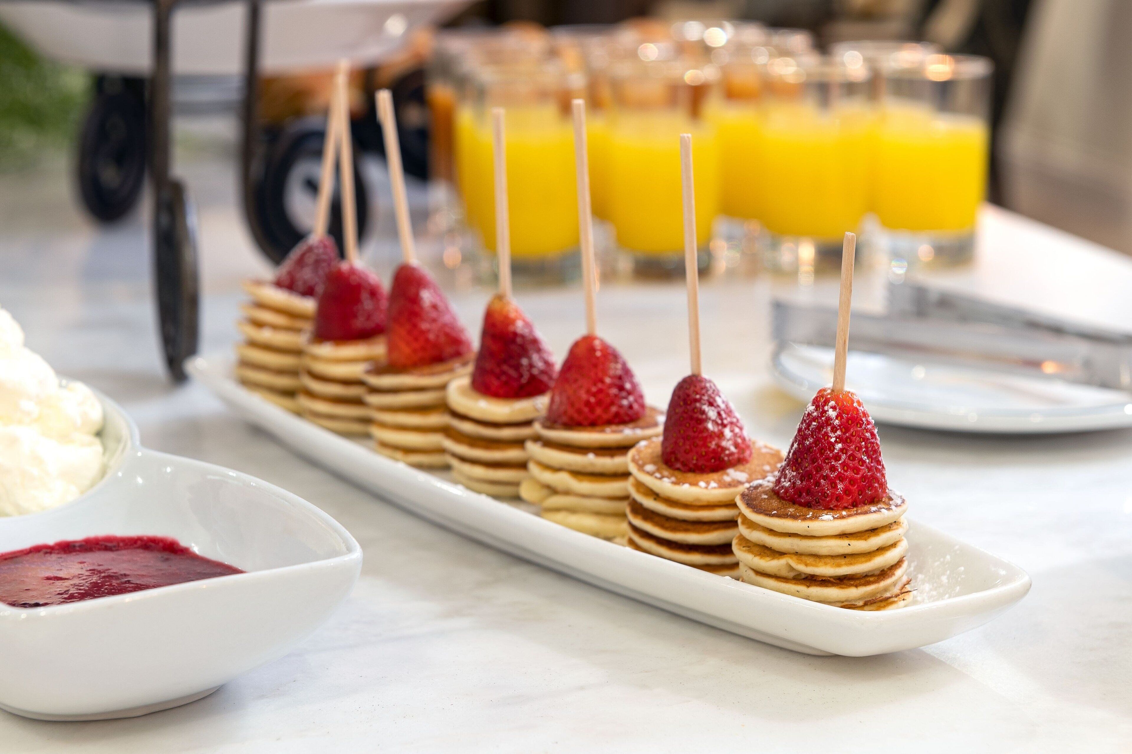 Ein Frühstücksbuffet mit Pfannkuchen, Erdbeeren und einer Marmeladenschale.