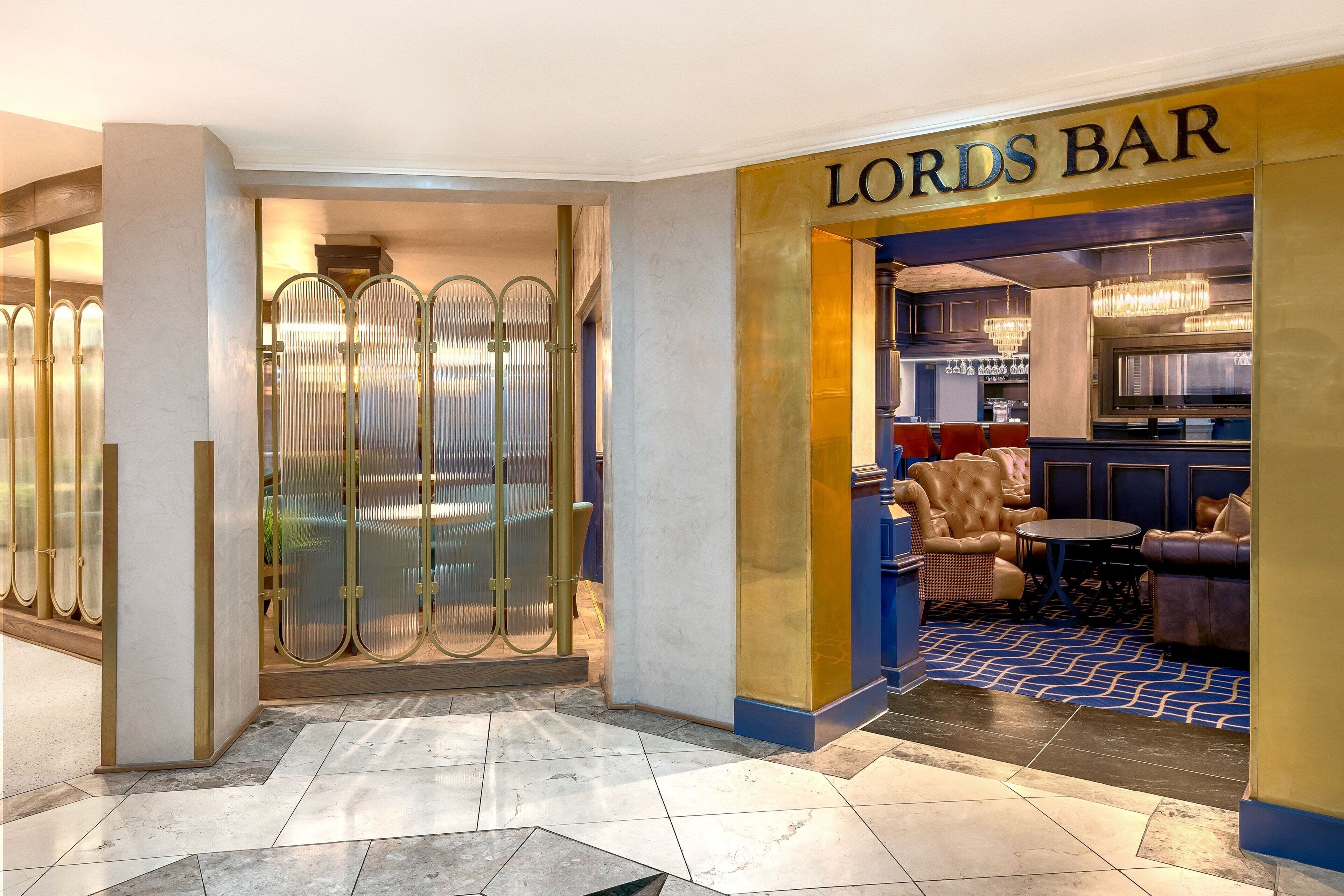 Een barruimte met een bord waarop 'LORDS BAR' staat, met lederen zitplaatsen en een vloer met patroon.