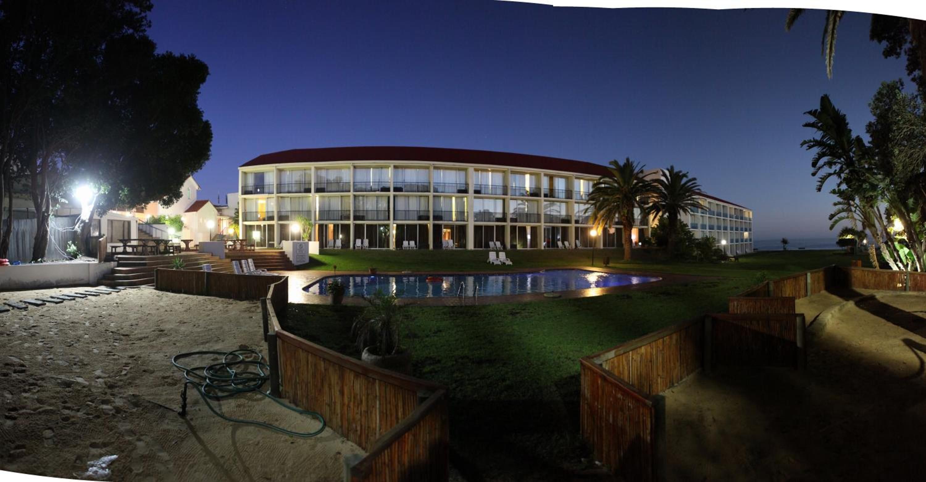 A hotel with a pool, outdoor seating, and a view of the ocean.