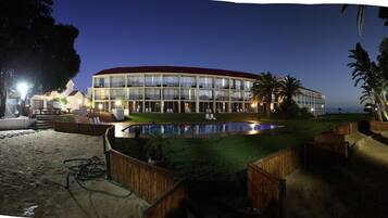 A hotel with a pool, outdoor seating, and a view of the ocean.