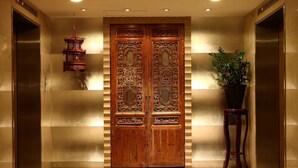 A wooden double door with intricate carvings, a hanging lantern, and a potted plant in a corner. - Gloria Prince Hotel Taipei (Taipei)