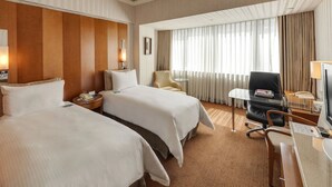 A hotel room with two beds, a desk, a chair, and a large window with curtains. - Gloria Prince Hotel Taipei (Taipei)