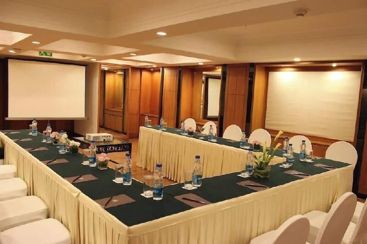 A conference room with a long table, chairs, a projector screen, and a whiteboard.