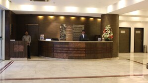 A reception desk with two attendants, a modern design, and a clean, polished floor. - The Hans Hotel New Delhi (New Delhi)