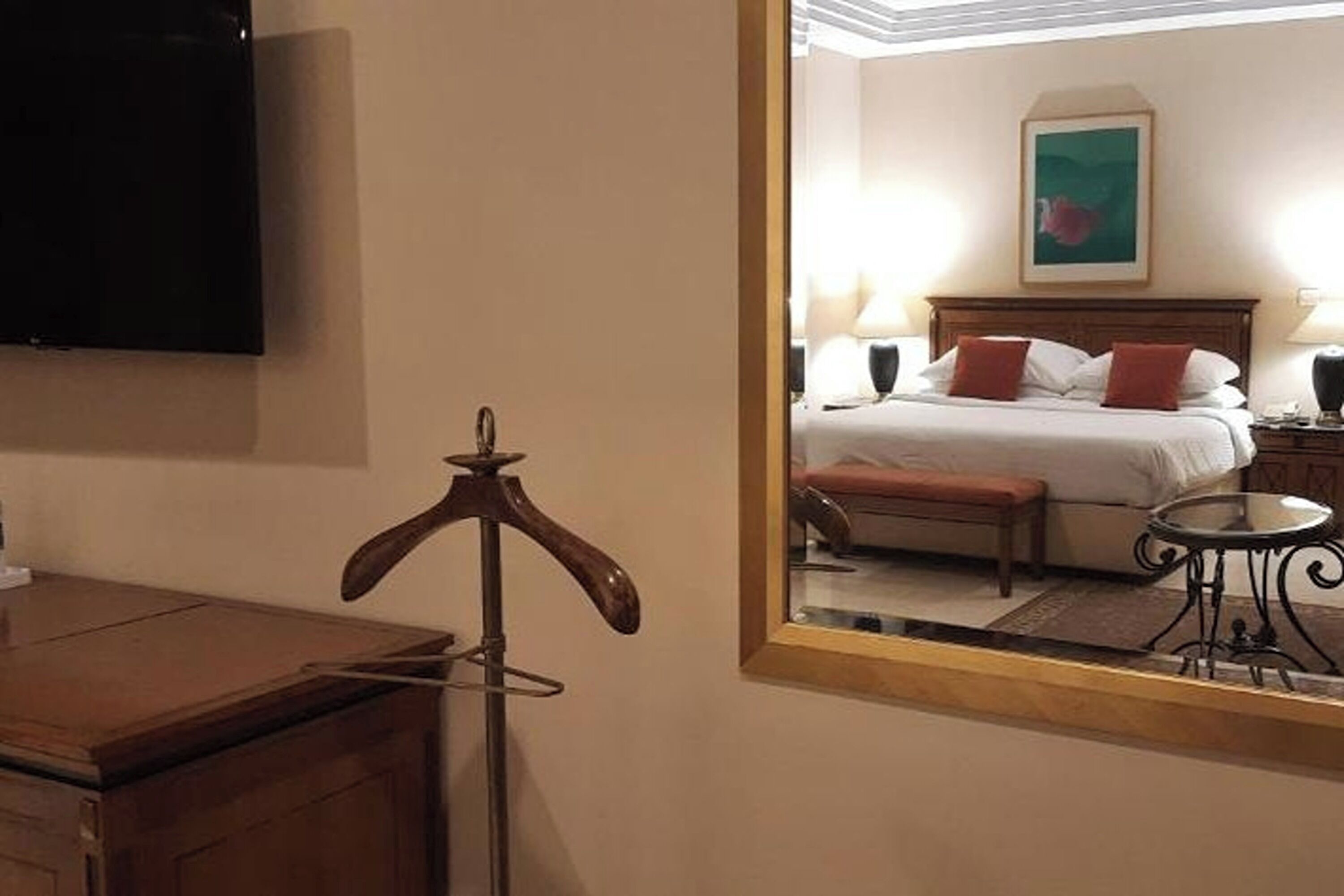 A hotel room with a bed, a bedside table, a chair, a desk, and a television.