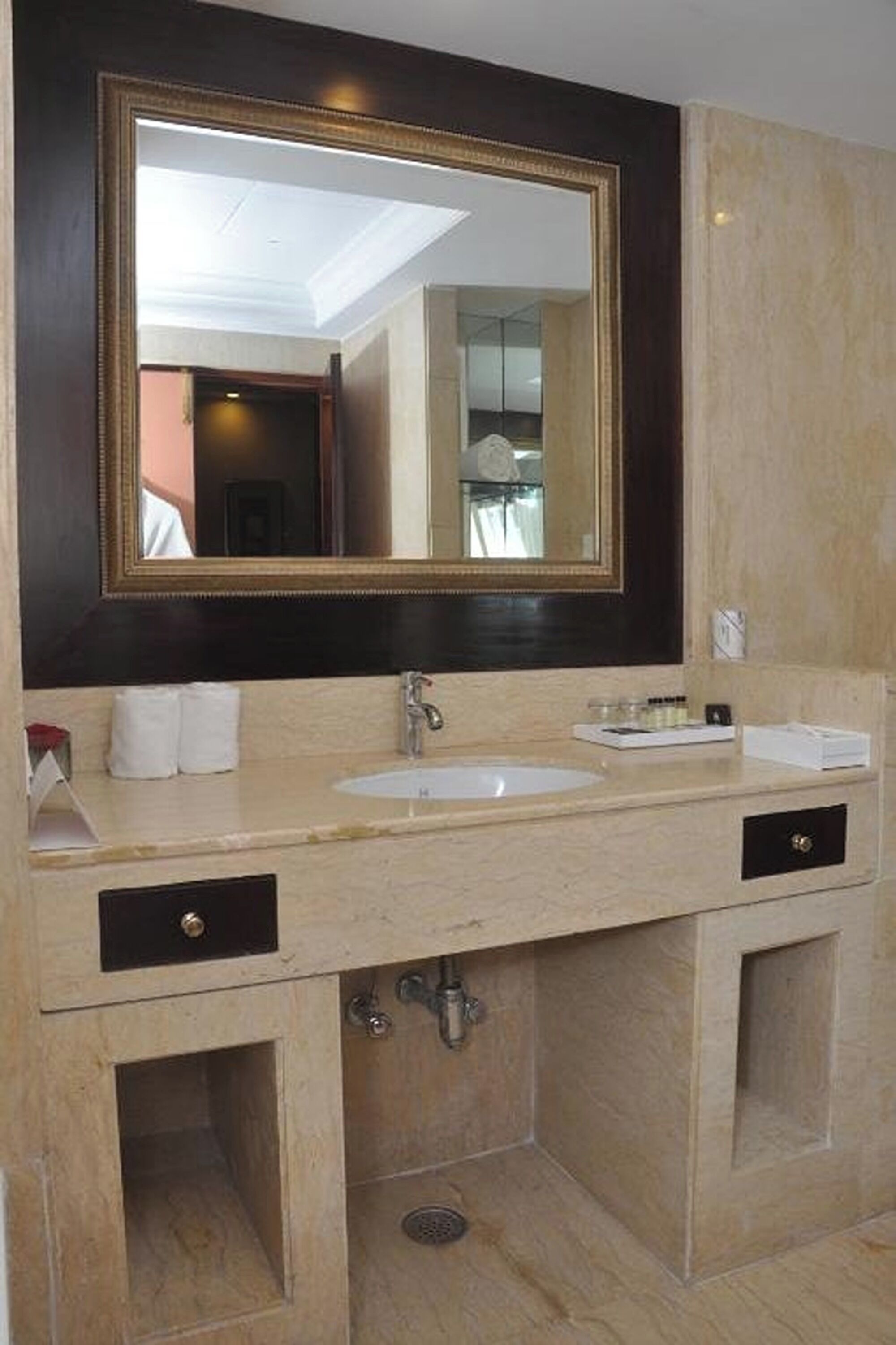 Une salle de bain avec un grand miroir, deux lavabos, un porte-serviettes et un meuble avec un tiroir.