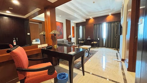 A hotel lobby with a reception desk, seating area, and a large mirror. - The Hans Hotel New Delhi (New Delhi)