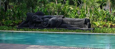 Una piscina con una escultura de piedra de una figura reclinada.