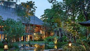 A resort with a pond, rocks, and tropical vegetation.