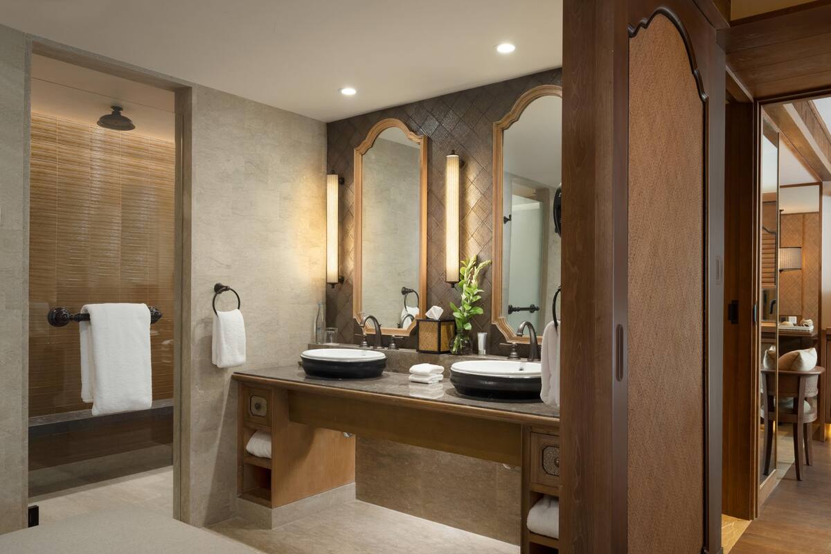 A modern bathroom with a double sink, large mirrors, and a towel rack.