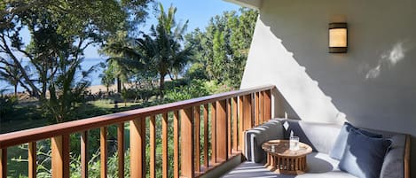 A balcony with a wooden railing, a cushioned seating area with a small round table, and a wall-mounted light fixture.