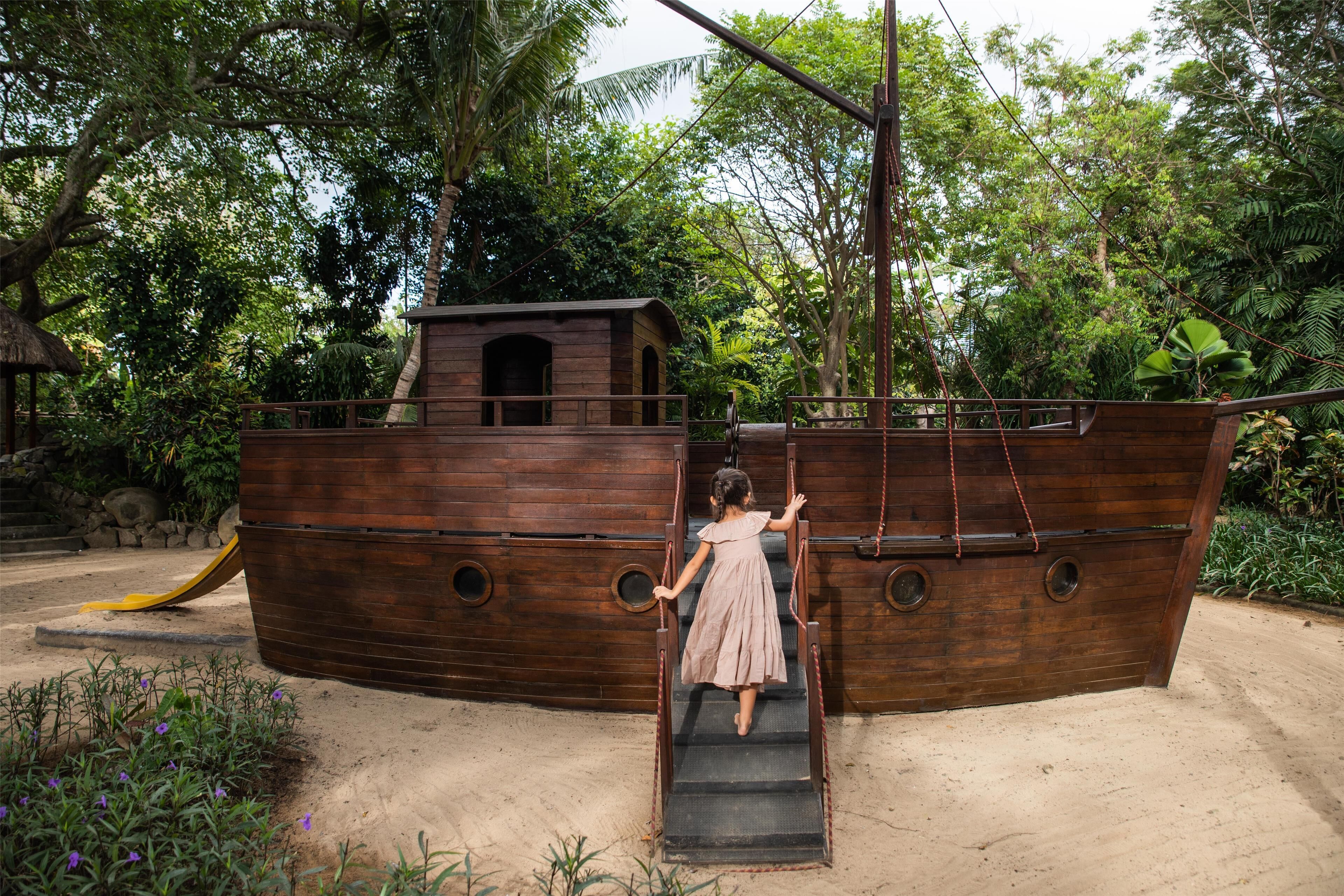 A wooden ship-themed play structure with a slide and stairs.