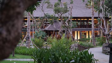A resort with a thatched-roof building, surrounded by lush greenery and a stone pathway.