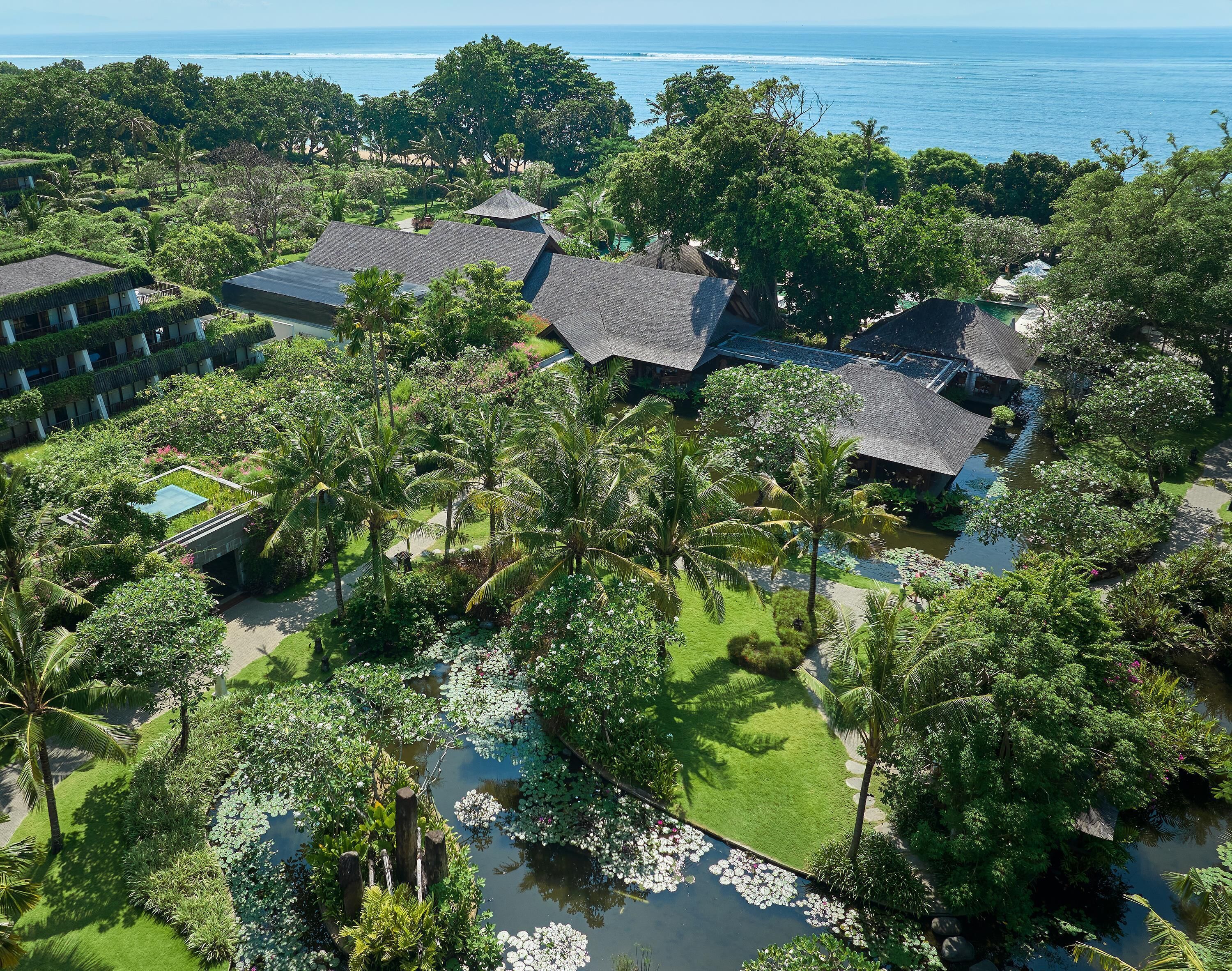 A resort with multiple buildings, lush greenery, and a body of water with lily pads.