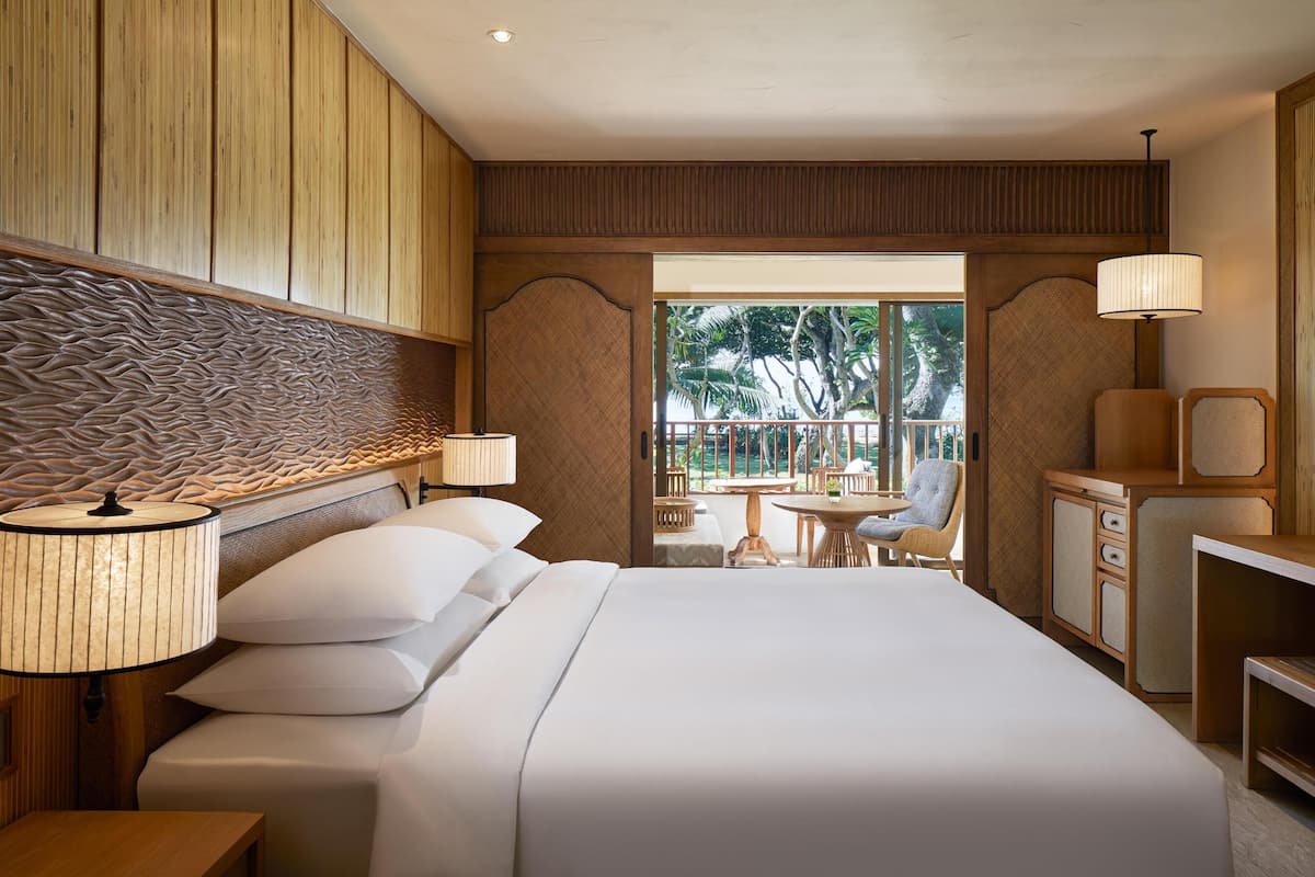 A hotel room with a large bed, a desk, a chair, and a view of the outdoors.